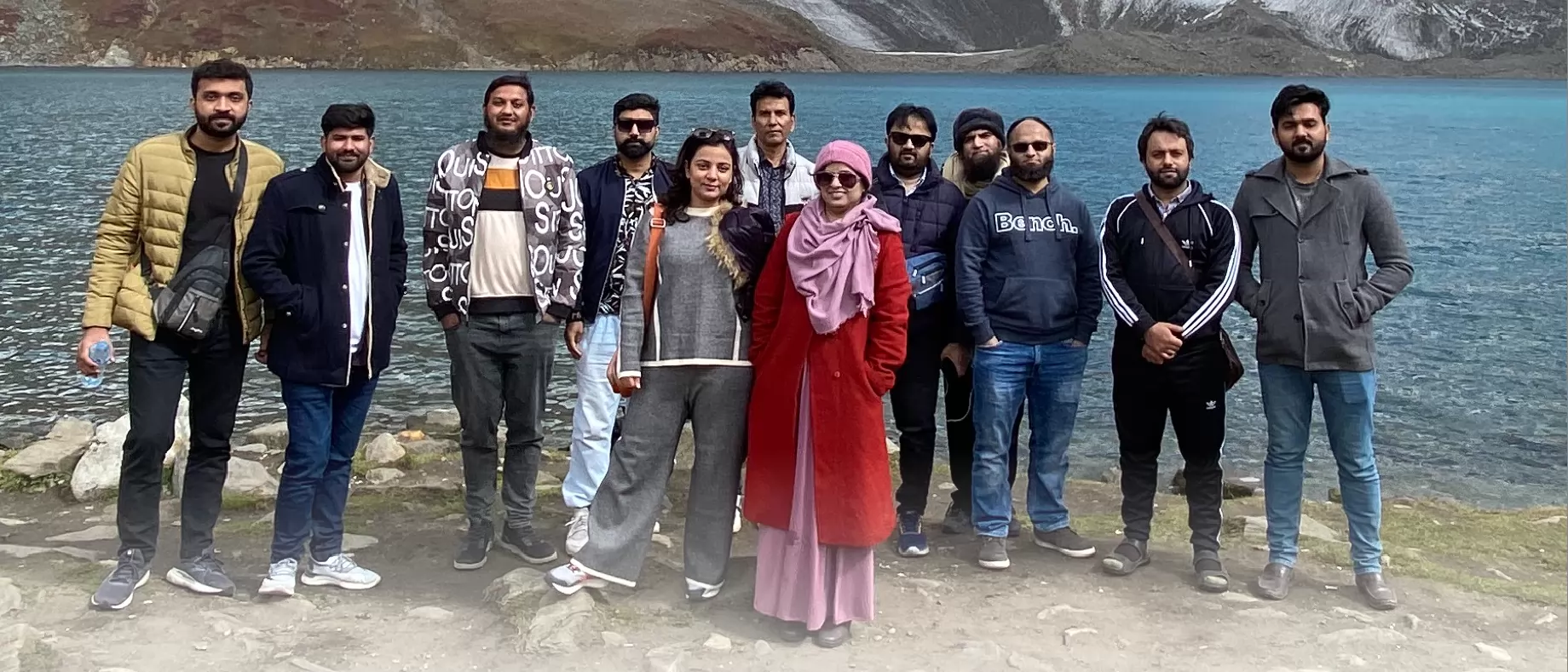 The whole A1Strategez team standing together on the shore of a glacial lake in the northern mountains