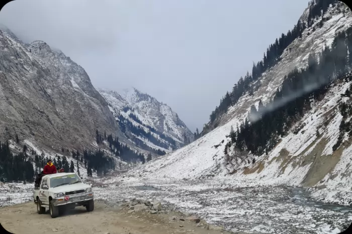 A pickup parked on a snow-lined mountain road