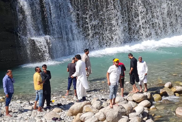 The team standing on the rocks beside a waterfall